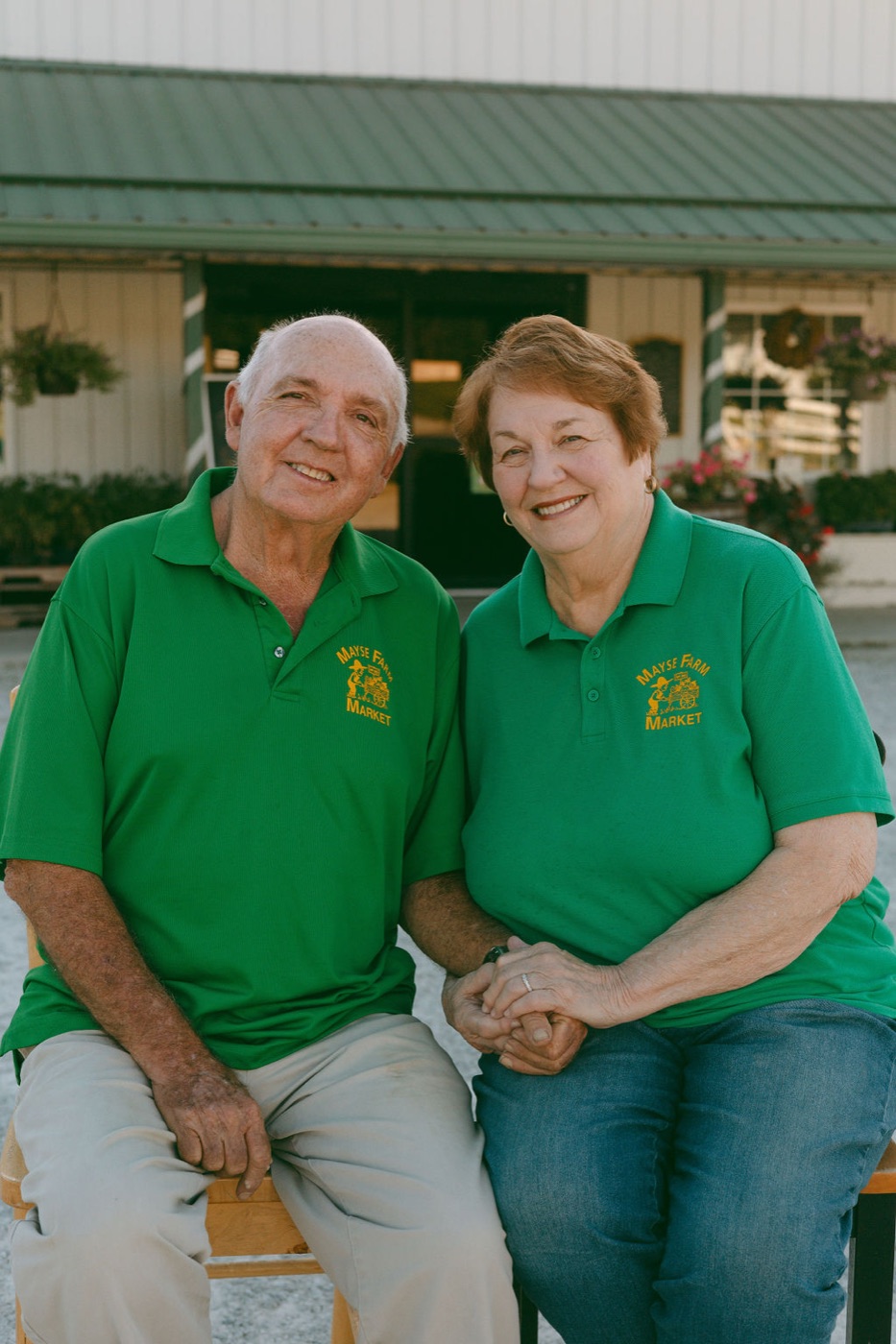 Paul and Sherrill Mayse sitting together in matching Mayse Farm Market green shirts